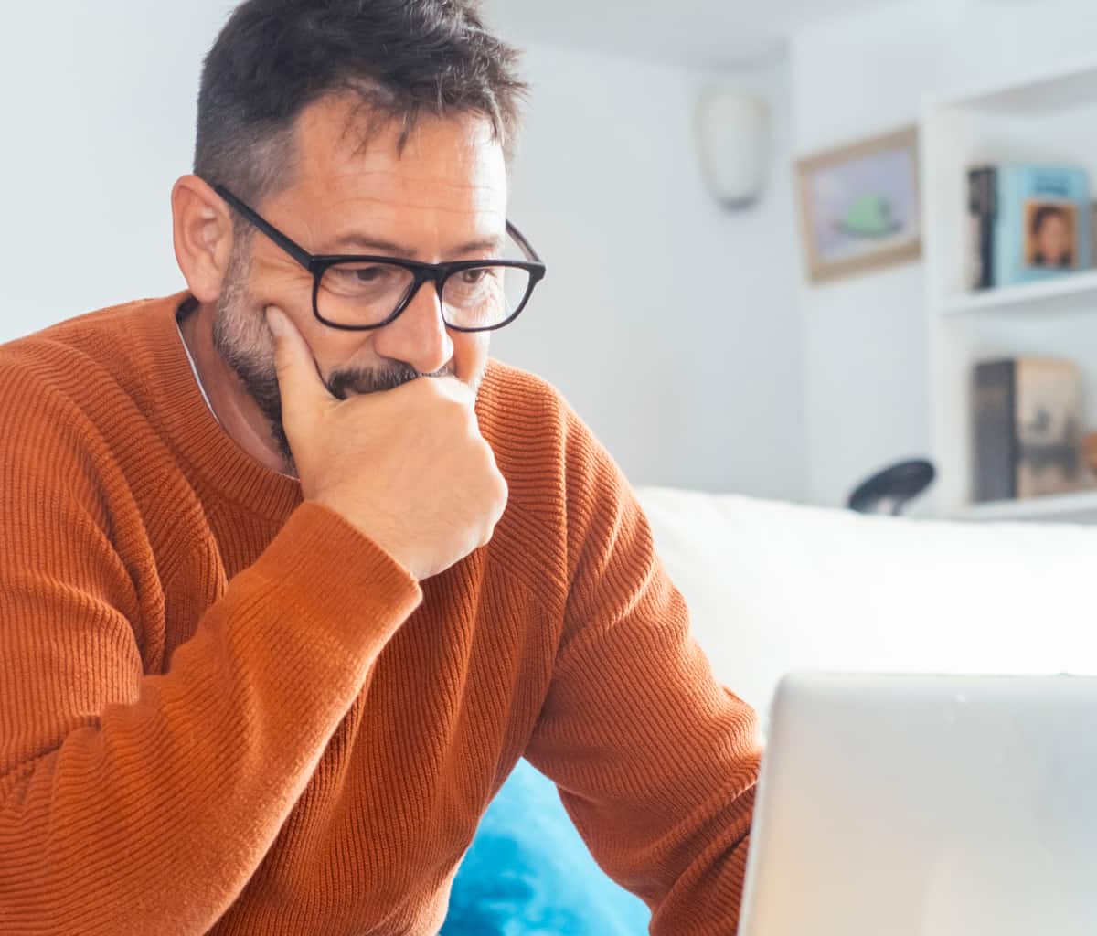 Man Wearing Glasses Looking Concerned While Looking At His Laptop Considering Scam Safety Online